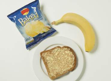 Packet of crisps, banana, and slice of toast with lower fat spread