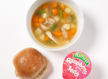 Homemade chicken and vegetable soup, a bread roll with lower fat spread, and a jelly pot