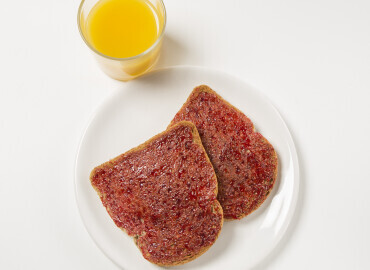 Glass of fresh orange juice and 2 thick slices of wholemeal toast with jam