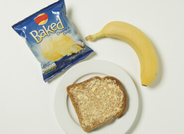 Packet of crisps, banana, and slice of toast with lower fat spread