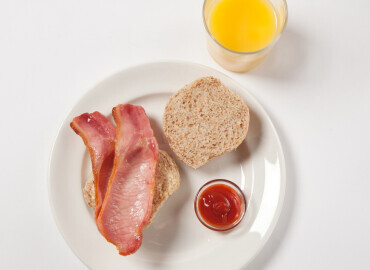 Bacon roll with tomato ketchup and a glass of fresh orange juice