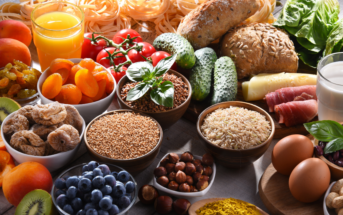 An assortment of different food types such as fruit and vegetables, bread, rice and nuts which form a balanced diet.