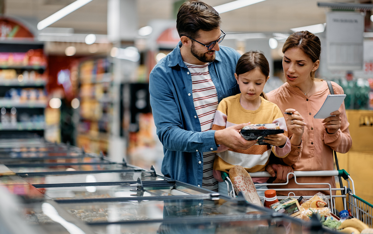 A mum, dad and their daughter standing in a supermarket. They're looking at a food label.
