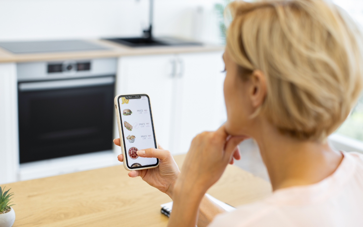 A woman looking through a food delivery platform on her smartphone