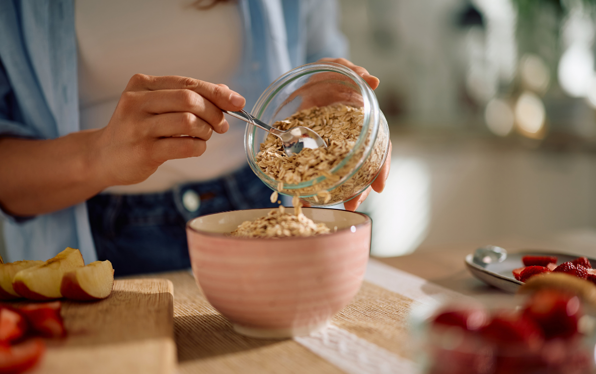 Woman putting oats into a porridge bowl