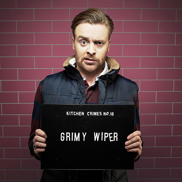 Mock mug shot photograph of a man holding a sign saying kitchen crimes number 16: grimy wiper