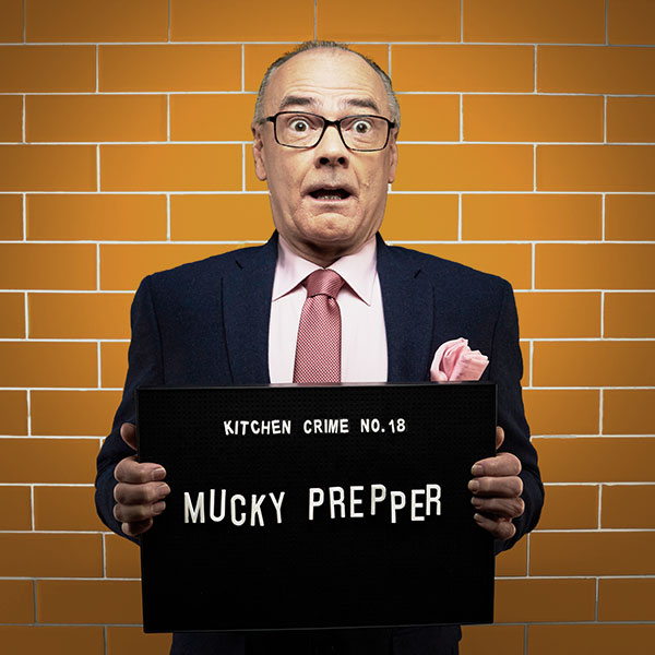 Mock mug shot photograph of a man holding a sign saying kitchen crimes number 18: mucky prepper