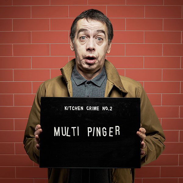 Mock mug shot photograph of a man holding a sign saying kitchen crimes number 2: multi pinger 