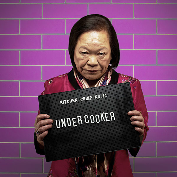 Mock mug shot photograph of a woman holding a sign saying kitchen crimes number 14: undercooker 